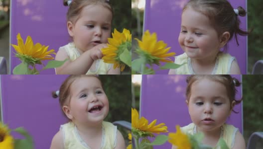 小女孩在后院和向日葵在户外玩耍的肖像——闻着香味，面带微笑高清在线视频素材下载