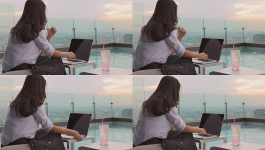夏日生活方式亚洲妇女放松和chill附近的豪华游泳池摩天大楼。一个亚洲女人在笔记本电脑上工作，模糊的背景摩天大楼，美丽的天空。高清在线视频素材下载