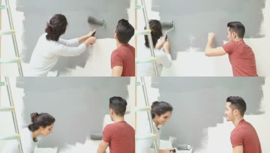 年轻夫妇用油漆滚筒刷墙高清在线视频素材下载