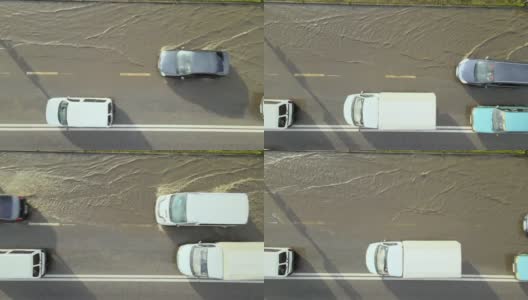 城市交通鸟瞰图，汽车行驶在暴雨后被淹没的街道上。道路排水系统的问题高清在线视频素材下载