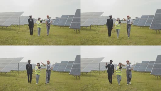 工人们在太阳能电站上行走。两名戴着白色头盔的检查人员和穿着制服的技术员在太阳能电站上行走。多种族工程师在户外检查光伏电池的工作高清在线视频素材下载
