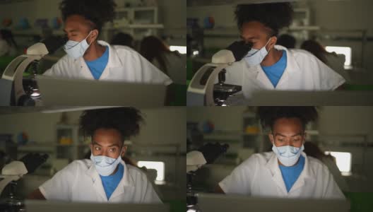 一个年轻人在实验室上课时戴着口罩使用笔记本电脑高清在线视频素材下载
