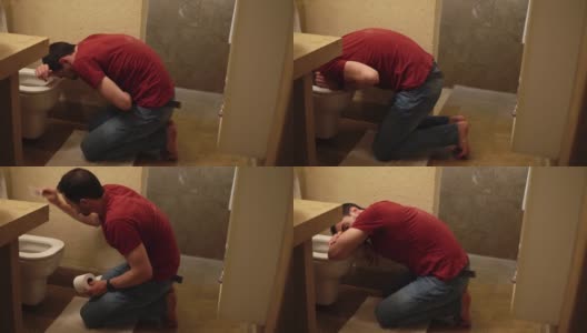 男子趴在马桶上呕吐，然后坐在厕所里用纸擦嘴高清在线视频素材下载
