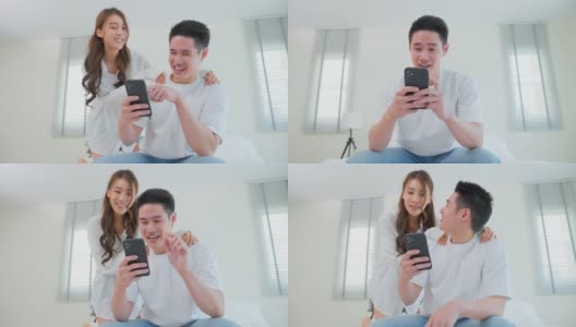 亚洲年轻情侣坐在床上一起使用手机。有吸引力的浪漫的新婚姻，男人和女人享受花空闲时间滚动智能手机，看在线新闻在卧室在家里。高清在线视频素材下载