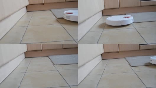 白色智能吸尘器清扫家里厨房的瓷砖地板。现代科技使生活更容易。特殊视频接收荷兰角高清在线视频素材下载