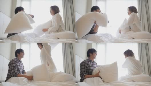 一对年轻夫妇在床上用枕头吵架高清在线视频素材下载