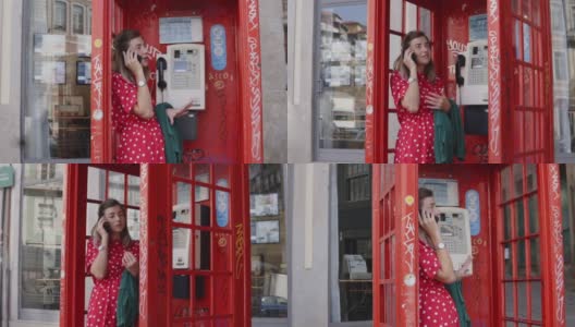 一个年轻的女人站在红色的旧电话亭里用她的小玩意说话高清在线视频素材下载