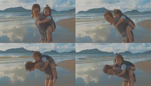 亚洲年轻母亲和小女儿在海滩上玩耍高清在线视频素材下载