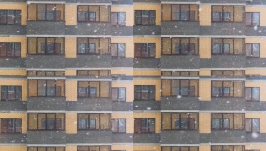 缓慢的运动。在一个大雪纷飞的冬天，城市里某公寓大楼的窗户前下起了一场大雪。雪花慢慢地飘落高清在线视频素材下载