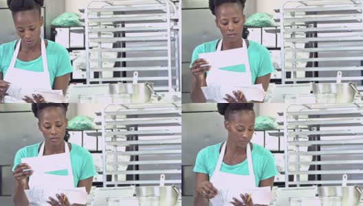 非裔美国妇女在面包店的厨房里付账单高清在线视频素材下载