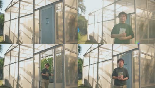 早上，自豪的亚裔中国女性水培垂直农场主带着收获的蔬菜走出温室，微笑着看着镜头高清在线视频素材下载