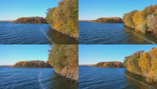 河边有五颜六色的树木。秋天的自然景观。秋天的风景很美。蓝色的湖在黄色的树的背景上。高清在线视频素材下载