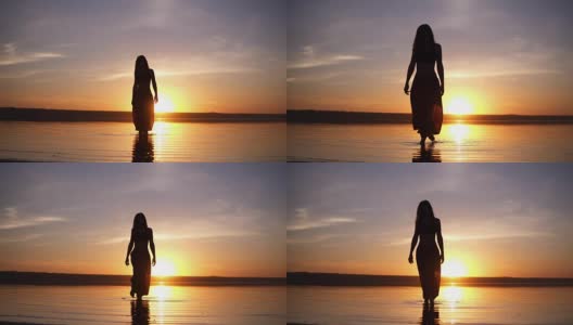 一个美丽的女人的剪影在早晨或傍晚的水面上的前镜头。穿着瑜伽裤的苗条女孩高清在线视频素材下载
