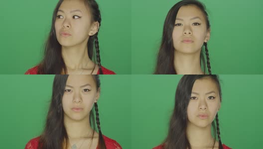 一个年轻的亚洲女人盯着，看起来很严肃，在一个绿色屏幕的工作室背景高清在线视频素材下载