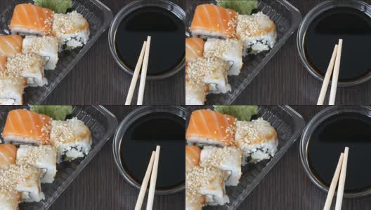 时髦的寿司摆放在黑色的木制背景上，旁边是酱油和中国竹竿。各种寿司卷配鲑鱼、鳗鱼、黄瓜虾等各种馅料高清在线视频素材下载