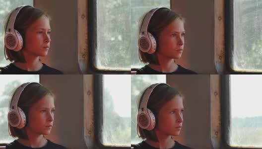 一辆行驶中的火车上，戴着耳机的女孩向窗外望去高清在线视频素材下载