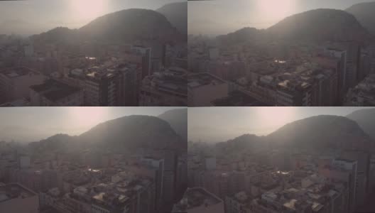 背光的空中朝向午后的太阳，俯瞰在巴西里约热内卢科帕卡巴纳海滩上的公寓楼，背景是山脉高清在线视频素材下载