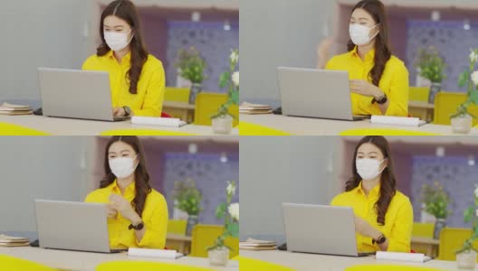 快乐的年轻亚洲商业女性戴着外科口罩与她的业务团队在现代办公室或联合办公空间进行在线视频电话会议，创业概念高清在线视频素材下载