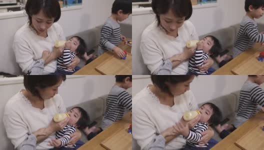 年轻的母亲在家里给她的男婴喂奶高清在线视频素材下载