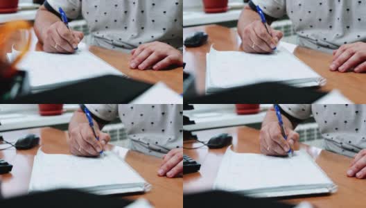 办公室里的一名员工坐在电脑旁边，在一个纸质的抄写本上做笔记。高清在线视频素材下载