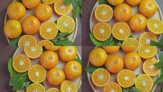 木盘上的鲜橘切片，花园木桌上的木盘上的橘子果。高清在线视频素材下载