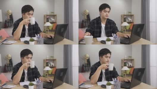 一名亚洲男性自由职业工人一边喝茶，一边在家里的电脑上继续工作，一边点头。高清在线视频素材下载