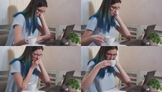 一位蓝色头发、戴着眼镜、疲惫不堪的女学生正在笔记本电脑上打字，一边喝着咖啡，一边打着哈欠。女孩坐在电脑前睡着了。工作中的倦怠概念高清在线视频素材下载