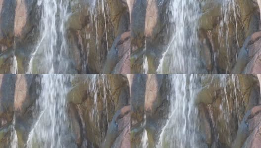 稳定的特写镜头，水从一个大岩壁上倾泻而下高清在线视频素材下载