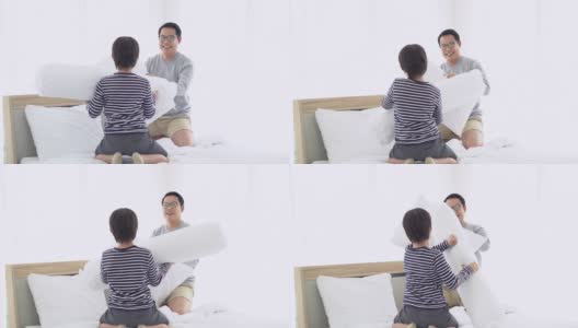 有趣的亚洲父亲和小儿子在家里卧室的床上和爸爸玩枕头大战。周末享受家庭休闲早晨生活方式活动在家里。高清在线视频素材下载