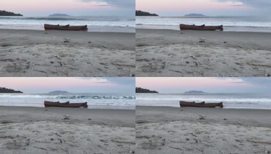 海浪冲向岸边，冲向躺在沙滩上的一根废弃的树干高清在线视频素材下载