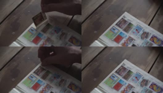 在黑暗的房间里，一个无法辨认的成年男性在桌子上插入邮票的特写镜头。高清在线视频素材下载