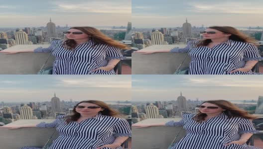 屋顶上的女孩俯瞰纽约市，日落时分曼哈顿的全景高清在线视频素材下载