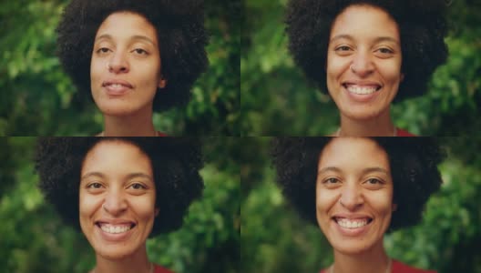 一个快乐的年轻拉丁人的近距离肖像与棕色的眼睛，非洲式的头发和鼻子穿孔为相机摆姿势。美丽多样的多民族黑人西班牙裔女性微笑在绿色的自然背景。高清在线视频素材下载
