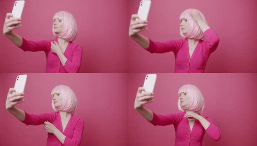 年轻漂亮的女人与粉红色的头发拍照，自我孤立的粉红色背景高清在线视频素材下载