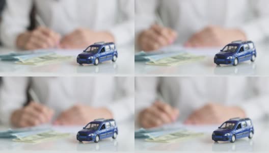 蓝色玩具车和背景钱的女人填写申请表高清在线视频素材下载