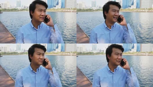 一个在户外玩手机的亚洲男人高清在线视频素材下载