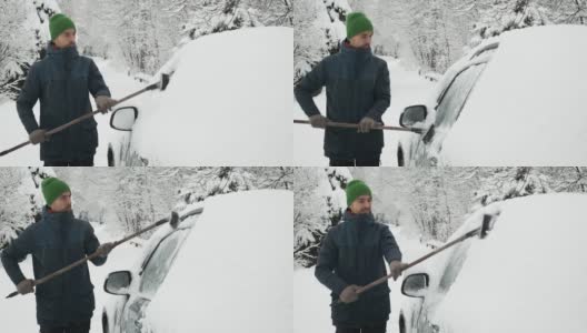 大雪过后，一名男子正在用刷子清洁被雪覆盖的汽车。暴风雪，恶劣的冬季天气，自然灾害。一个人正在清理他的汽车侧窗上的积雪。高清在线视频素材下载