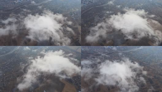 高空鸟瞰图，远处的城市被暴雨前形成的蓬松的积云所覆盖。飞机角度多云的景观高清在线视频素材下载