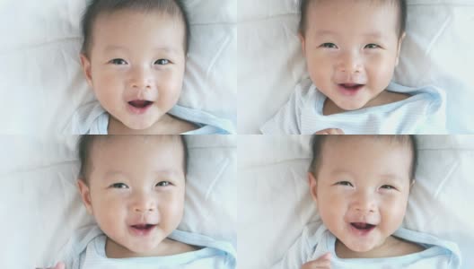 贴近可爱可爱的小女孩在白色床单上微笑的脸，带着快乐积极的情绪，宝宝快乐的时间概念高清在线视频素材下载
