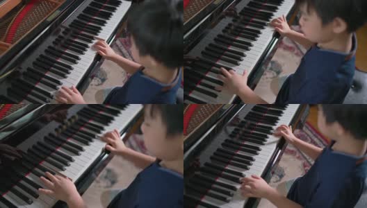 俯视图亚洲男孩在客厅弹奏三角钢琴和选择性的焦点在手上。在线练习和学习。业余爱好和在家学习。快乐的一天和家庭的概念。活动和生活方式。高清在线视频素材下载