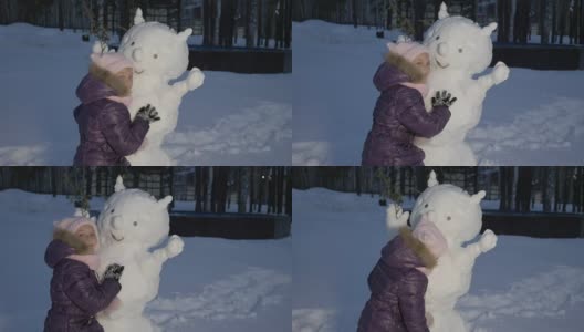 快乐的小女孩拥抱雪人在晚上冬天在乡村散步高清在线视频素材下载