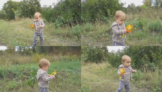 一个小男孩手里拿着一个玩具，正在公园外的秋日里迈出他的第一步。高清在线视频素材下载