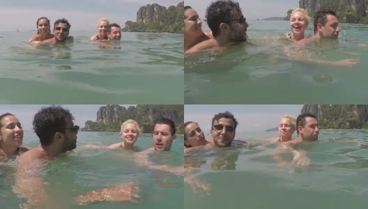 两名男子抱着在海水里游泳的女子谈话POV，暑假里的年轻游客高清在线视频素材下载