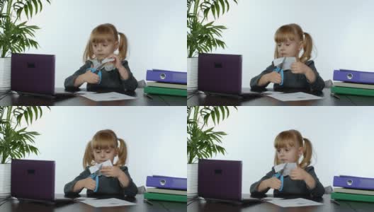 一个小女孩坐在桌子旁用剪刀剪出纸的形状学习功课高清在线视频素材下载