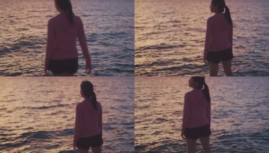 一位美丽的亚洲女跑步者站在沙滩上看海景。高清在线视频素材下载