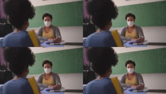 一名十几岁的学生戴着口罩在教室里与老师交谈高清在线视频素材下载