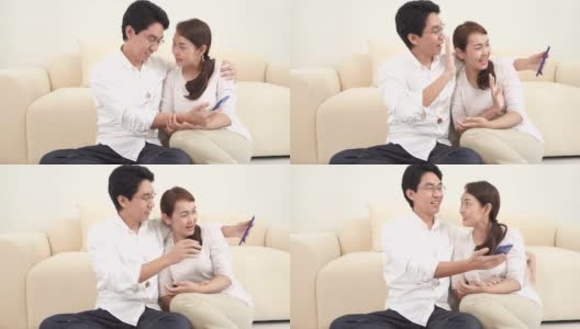 幸福的亚洲夫妇在家里客厅用智能手机与朋友和家人进行视频通话。居家隔离，保持社交距离，扬已婚观念。高清在线视频素材下载