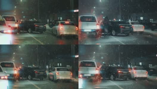 在傍晚雪天的交通高峰期，发生车祸或交通事故。两辆损坏的汽车在暴风雪中闪烁着车灯。慢动作高清在线视频素材下载