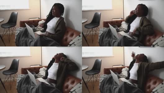 一个年轻女子在沙发上放松地用她的笔记本电脑，看起来像是在家里睡觉的4k视频片段高清在线视频素材下载