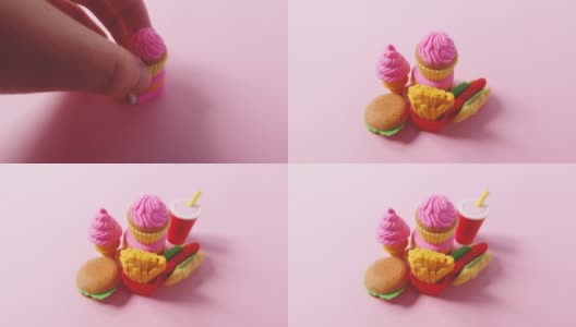各种快餐特写的微缩模型。人类的手在明亮的粉红色背景上铺上美国快餐的小型玩具。4k延时搞笑微距视频。高清在线视频素材下载